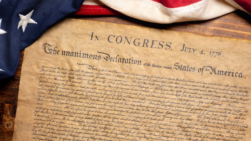 an aged copy of the Declaration of Independence flanked by an American flag at the top of the page