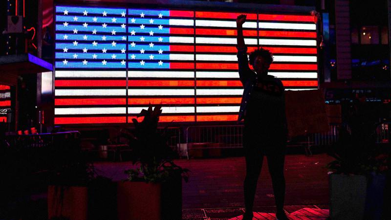 statue of a woman silhouetted against a glowing American flag